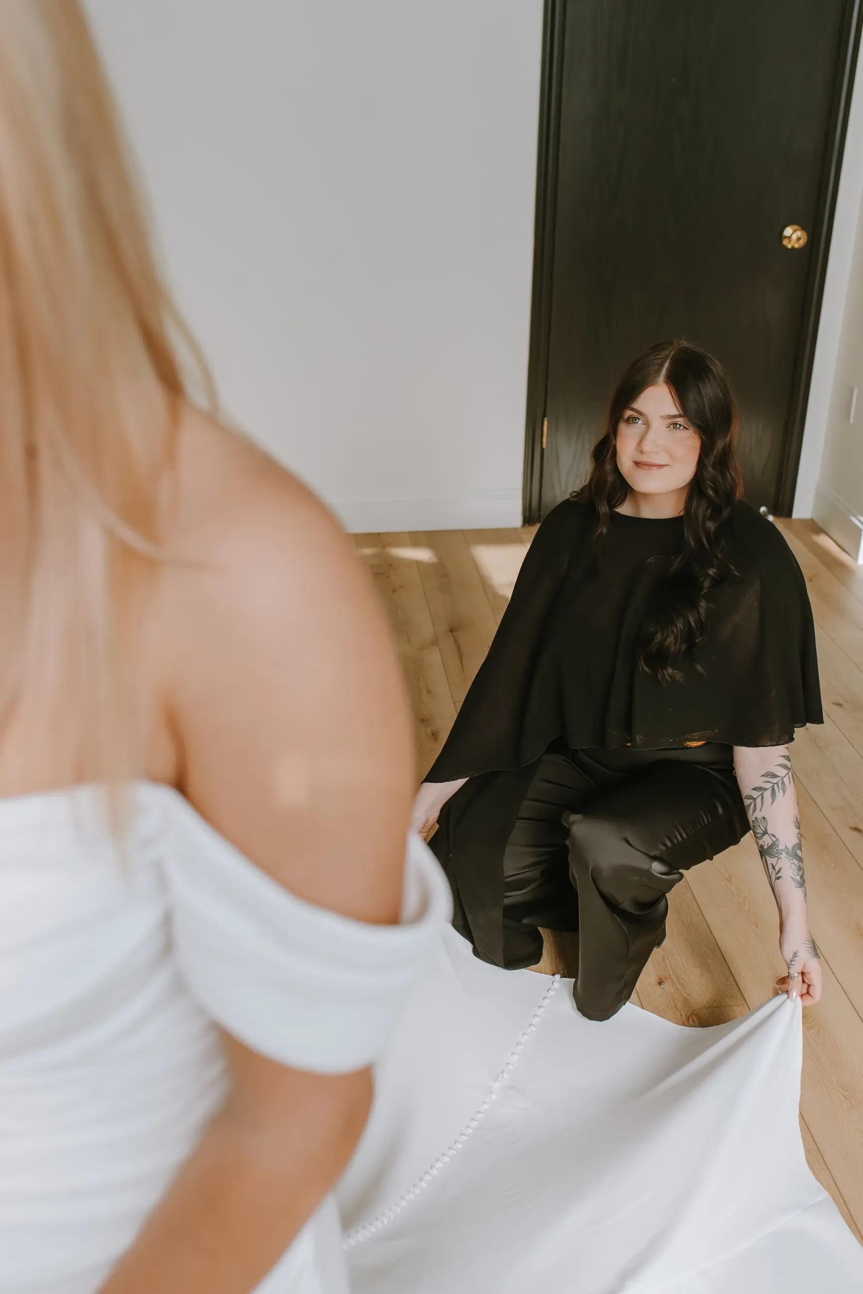 image shows a stylist helping a bride with her train